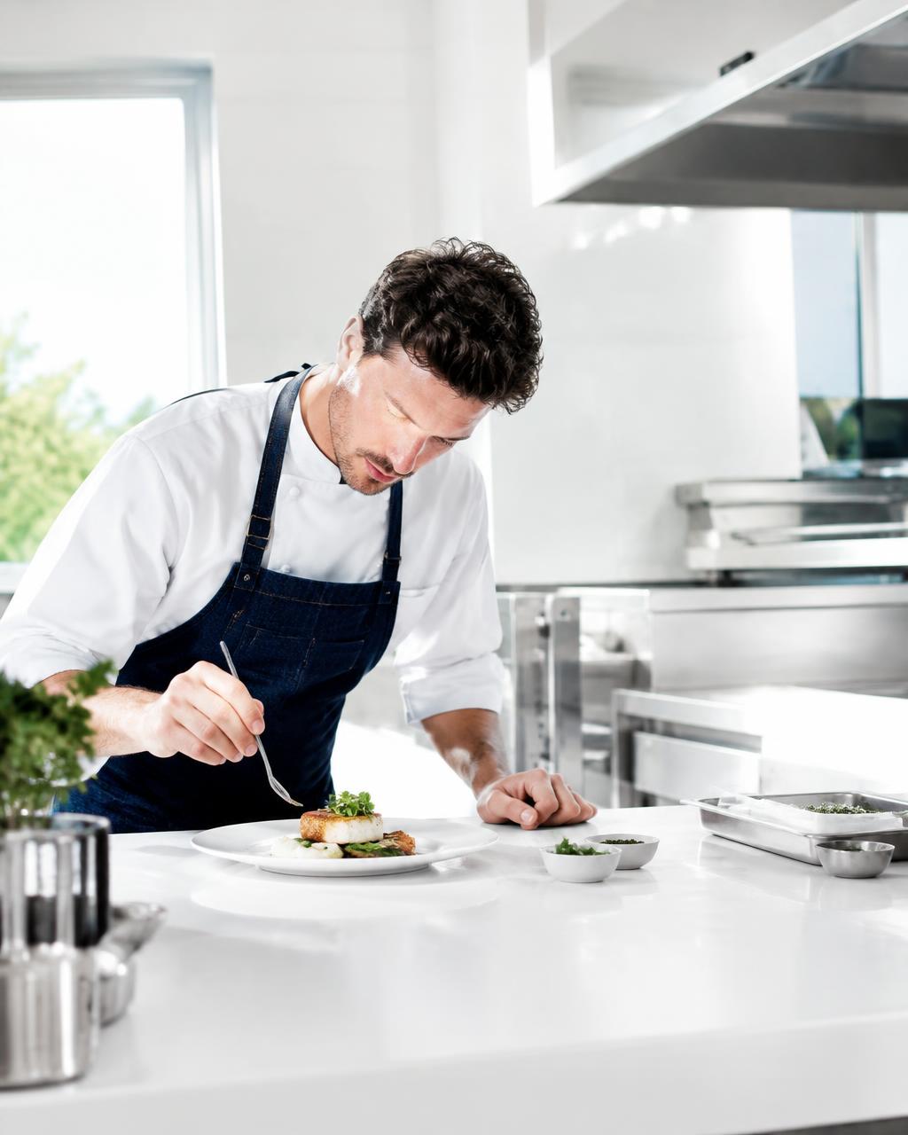 Chef plating in a bright professional kitchen